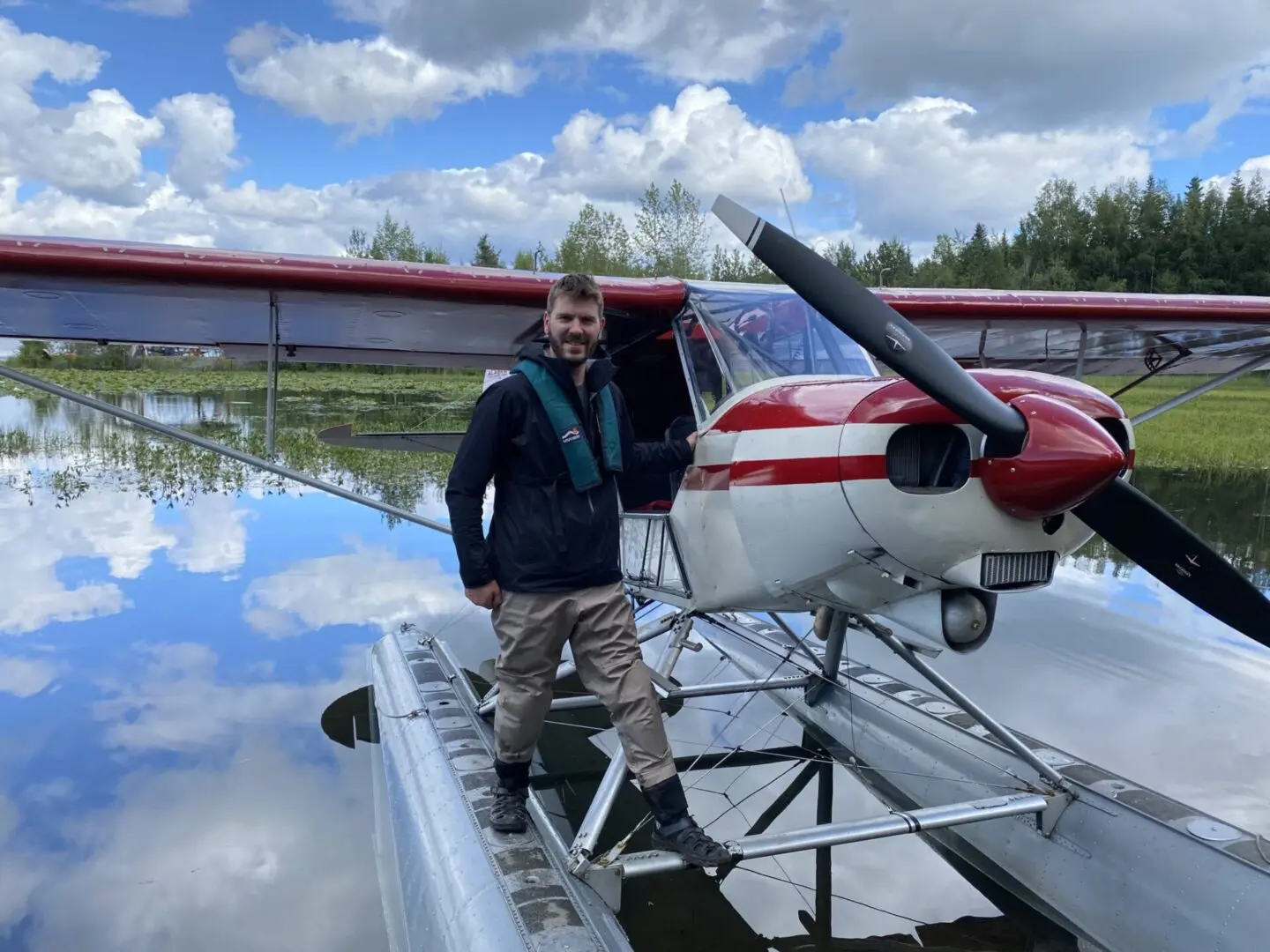 A man standing next to a plane in the water.