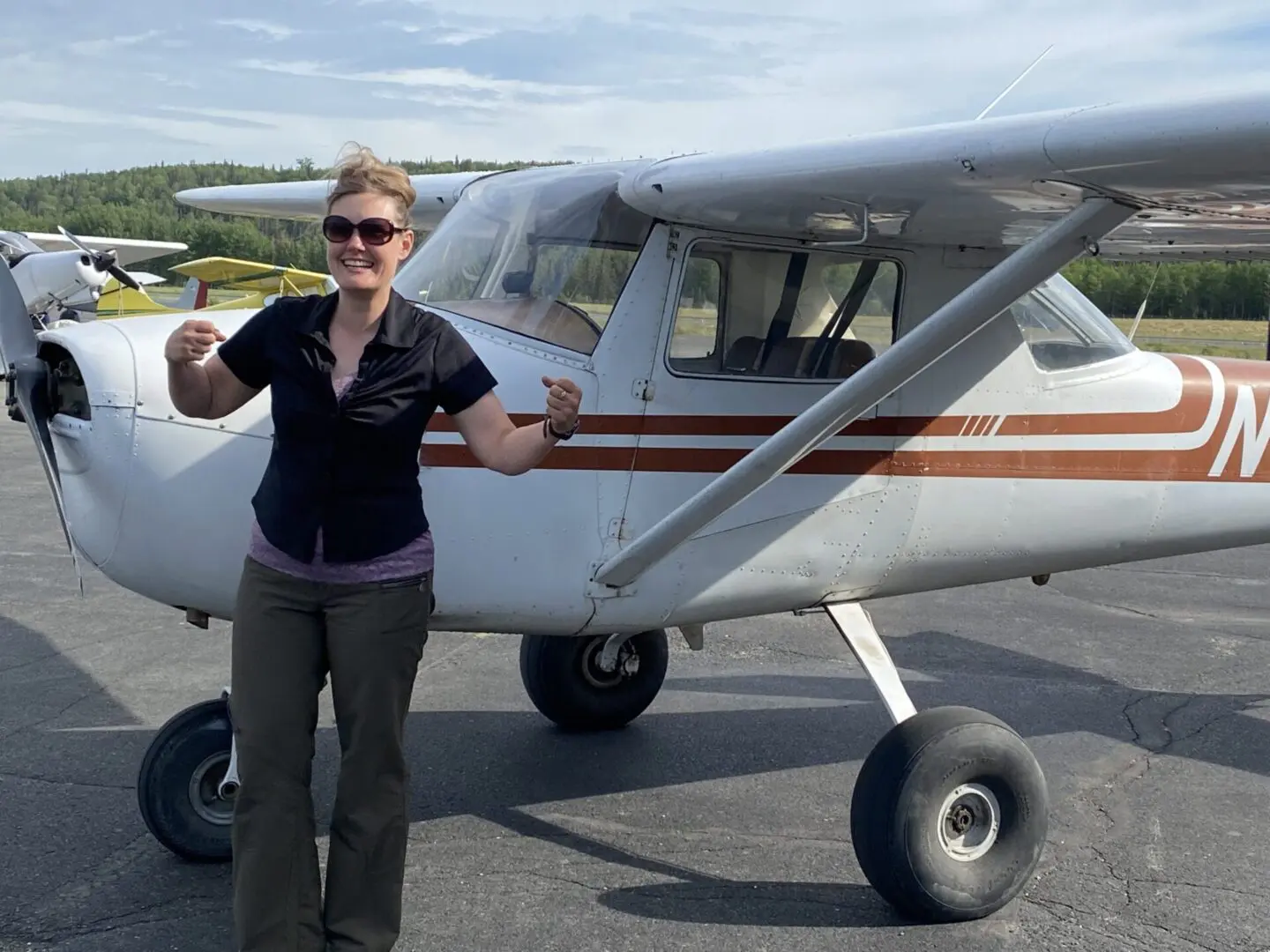 A woman standing in front of a small airplane.