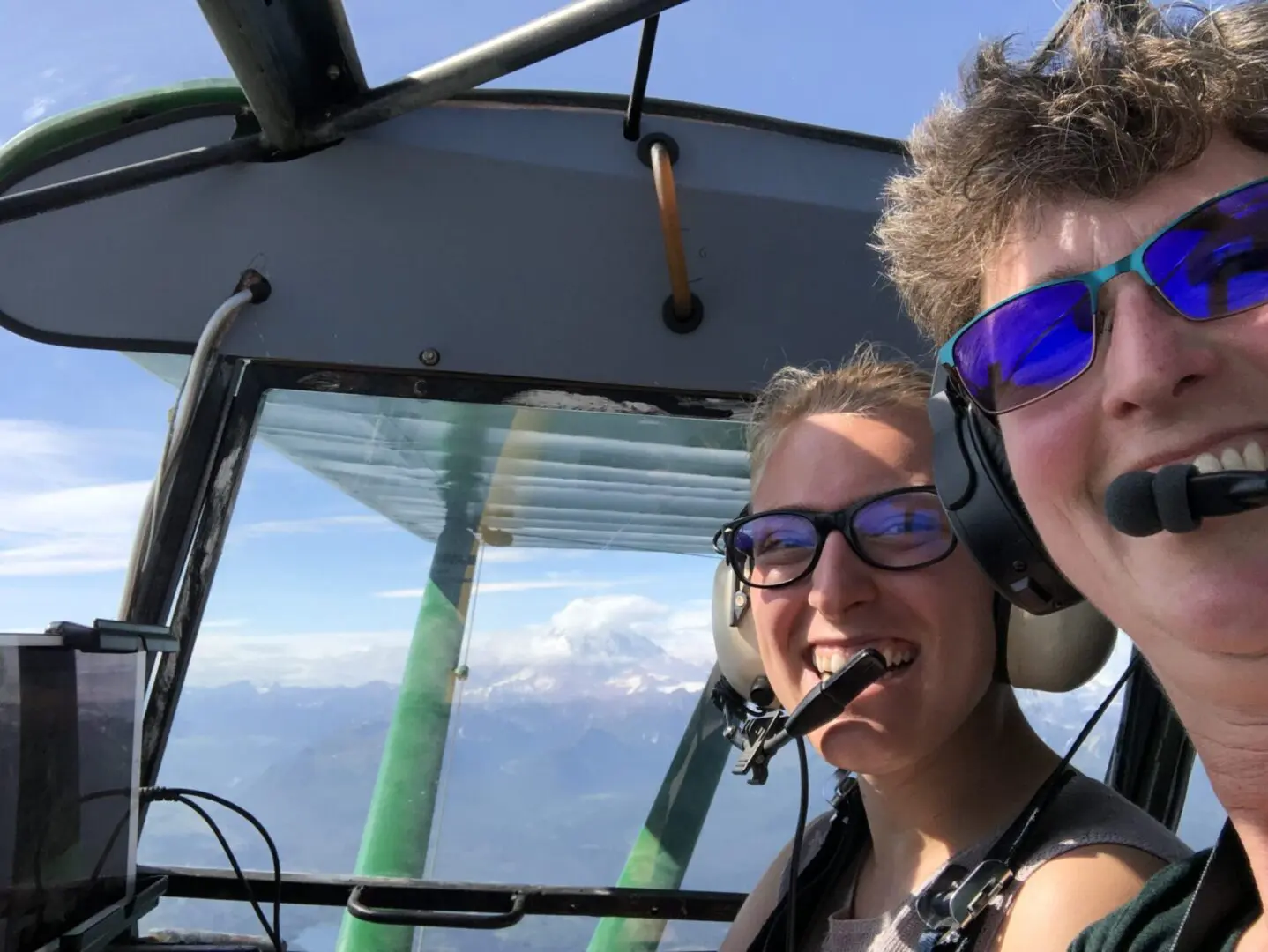 Two women smiling in the cockpit of a plane.