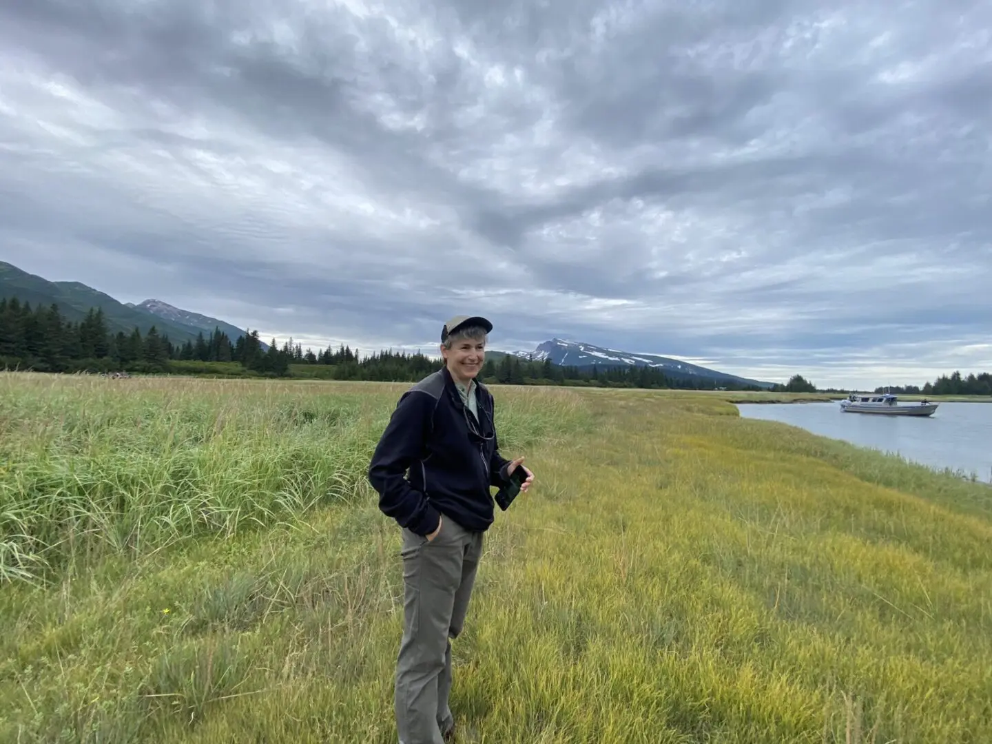 A man standing on a grassy field next to a body of water.