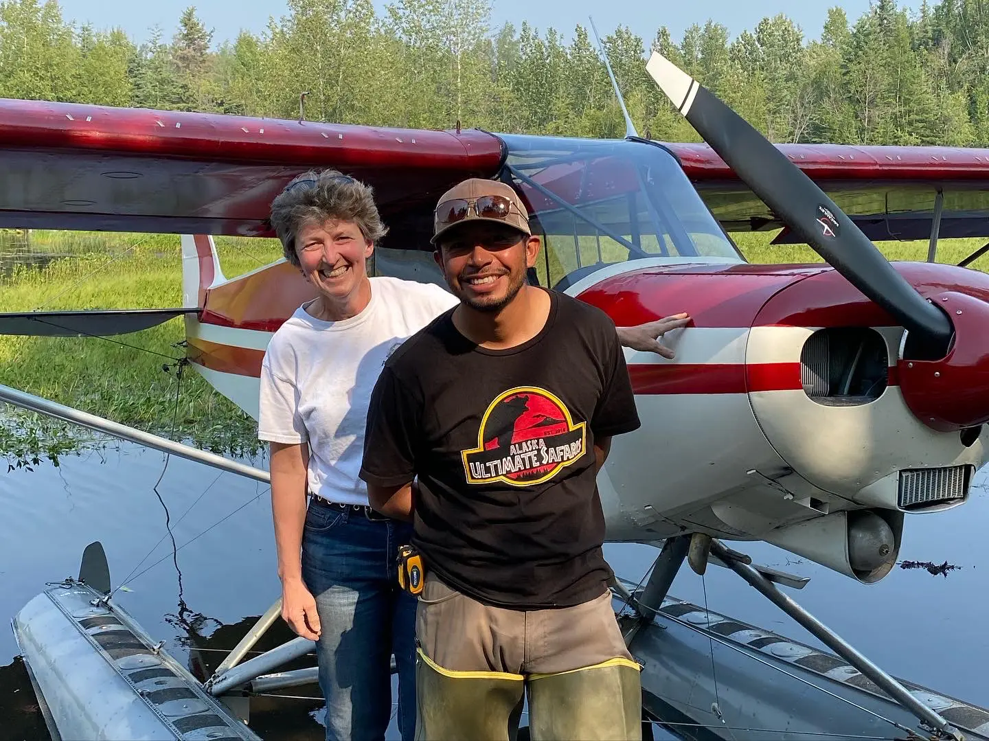 A man and woman standing next to a plane in the water.