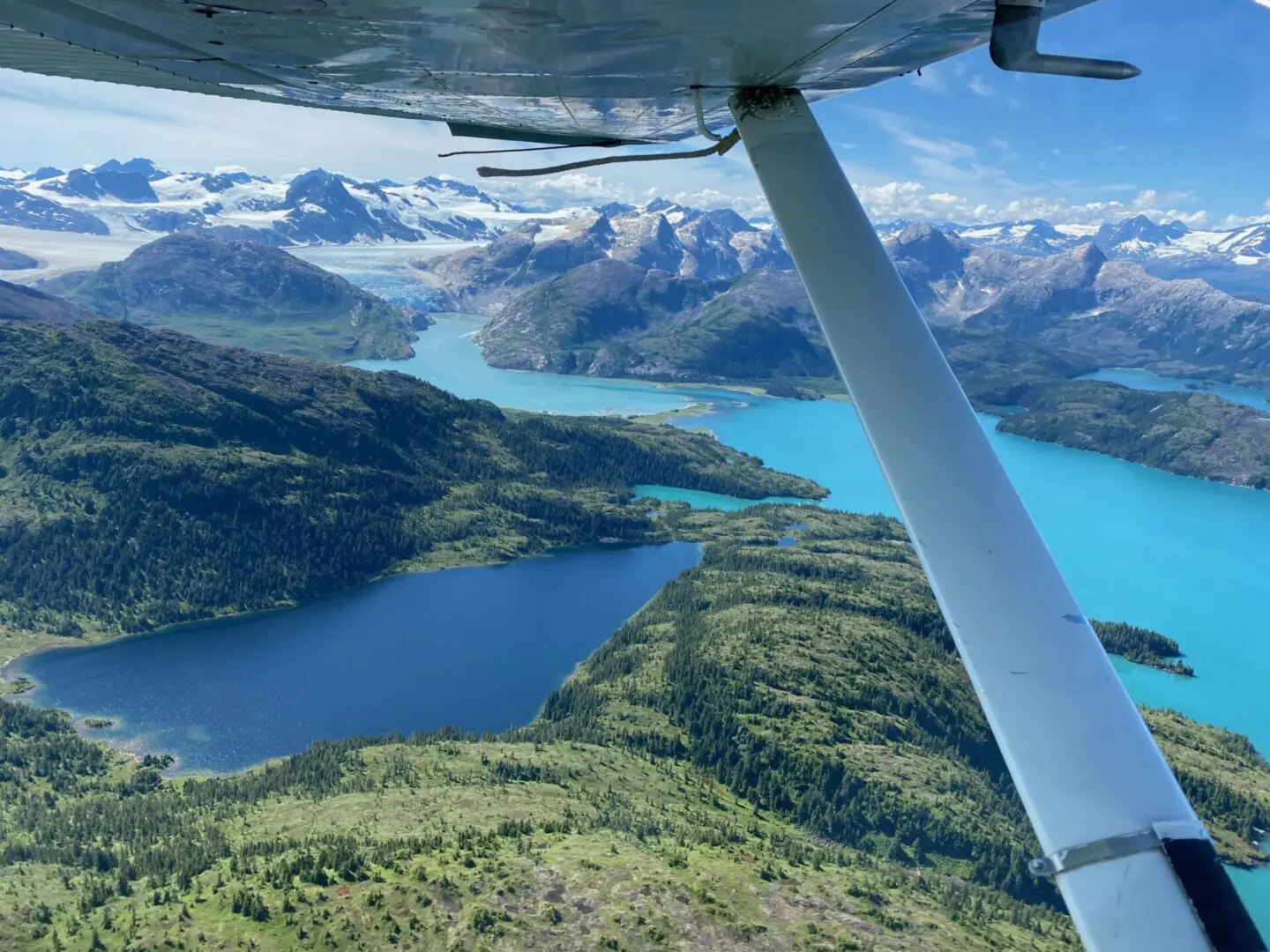 A view from the wing of a plane over a lake and mountains.