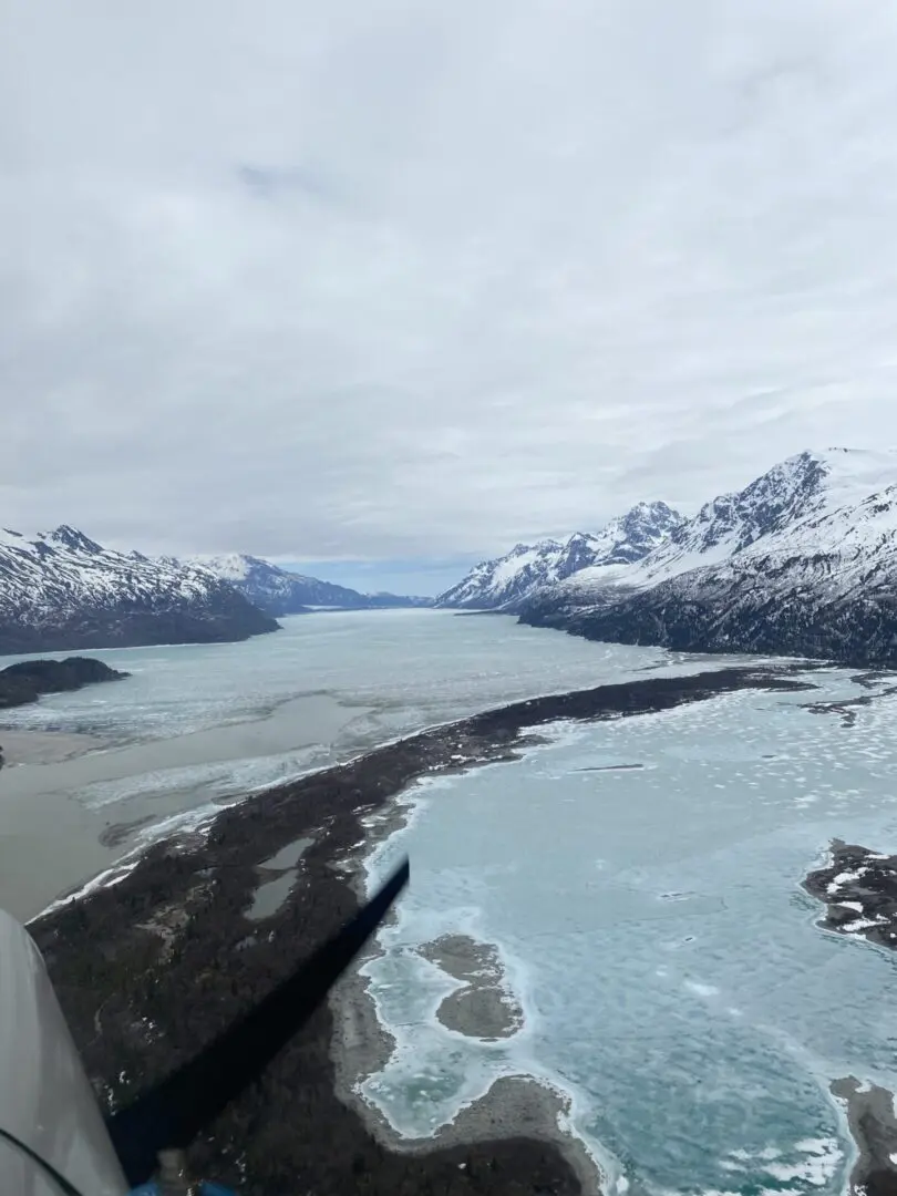 A plane flying over a lake and mountains.