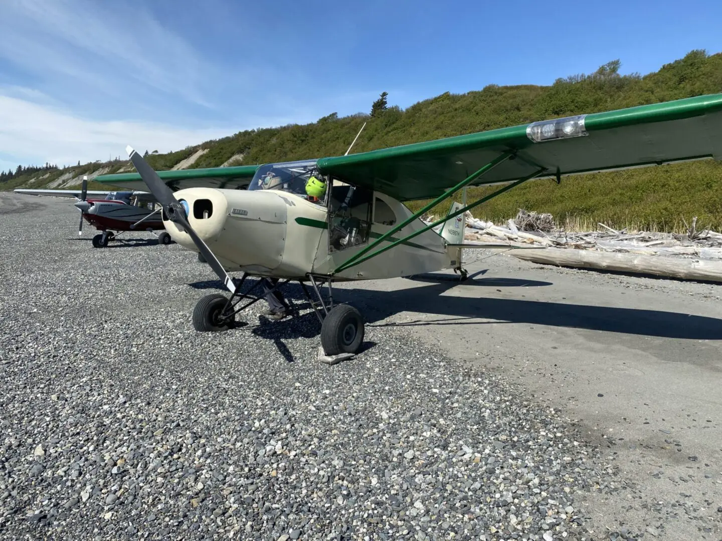 A small plane parked on a gravel road next to a body of water.