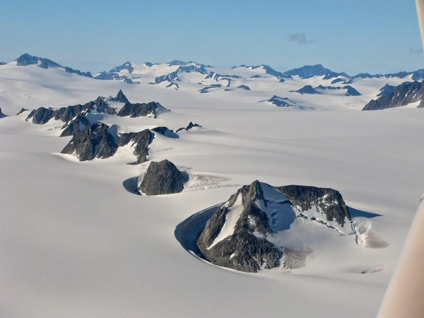 A plane flying over a large area of snow and mountains.