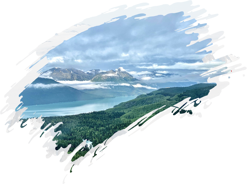 A picture of a mountain and lake with clouds in the background.